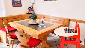Taula de fusta amb coixinets vermells, una taula petita blanca i una cadira vermella amb coixí vellutat.