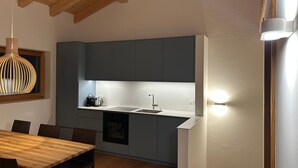Eine moderne Küche mit dunkelblauen Schränken, einem Holztisch und einer hängenden Pendelleuchte.