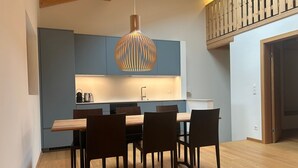Eine moderne Küche mit blauen Schränken, einem Holztisch und einer hängenden Pendelleuchte.