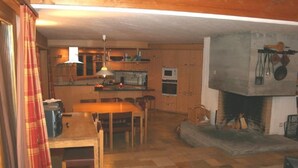 Una cocina acogedora con armarios de madera, una mesa de comedor y una chimenea.