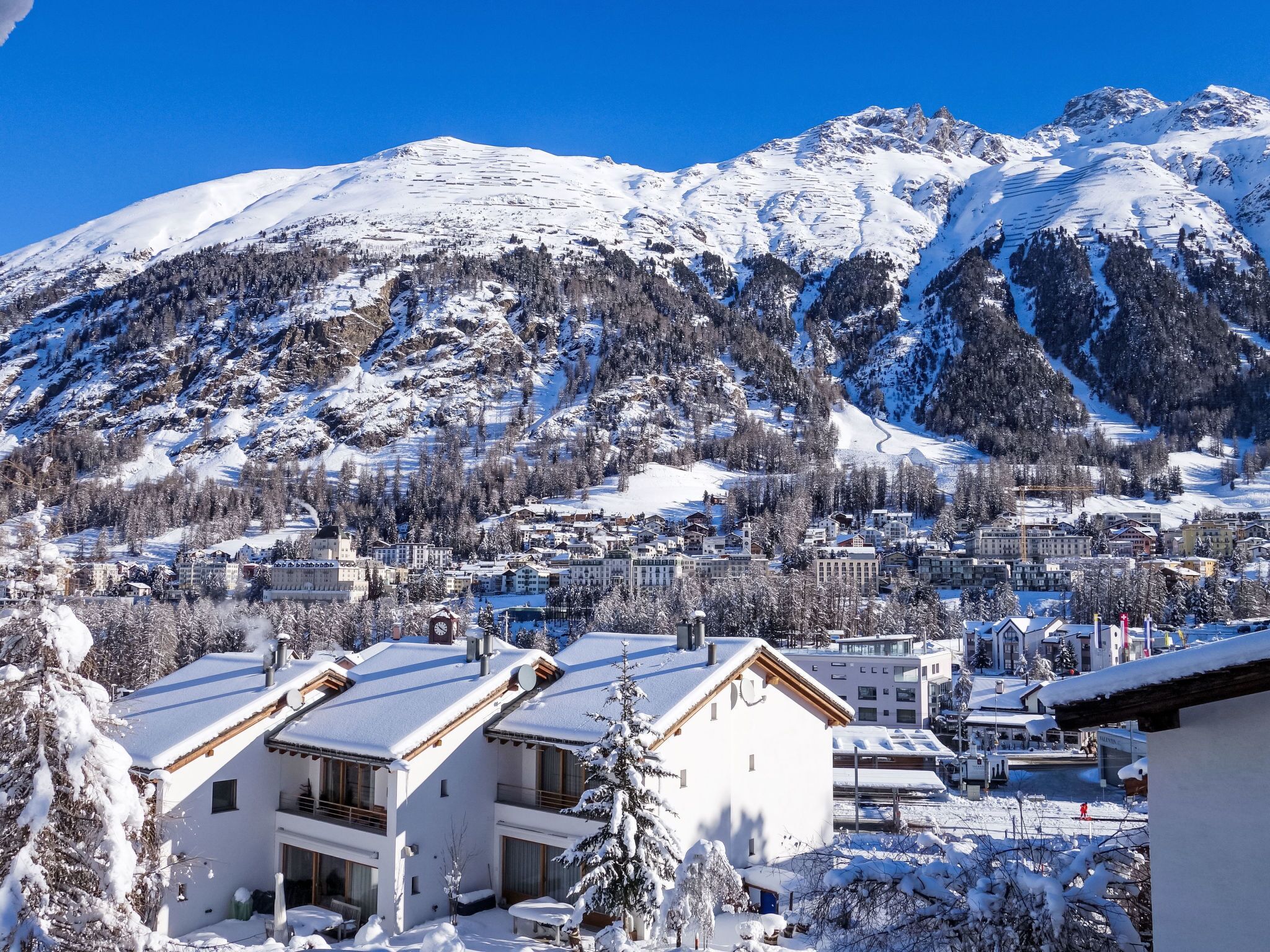 Eine verschneite Bergstadt mit Gebäuden und einer Skipiste.