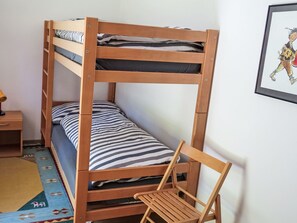 A bunk bed with a wooden frame, a single bed below, a chair, a small table, and a rug. - Chesa Suot God by Interhome (Pontresina)