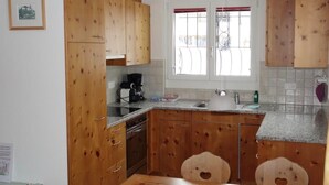 Eine Küche mit Holzausstattung, einer Kaffeemaschine und einem Fenster mit roten Vorhängen.