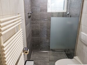 Un baño con ducha, inodoro y un radiador.