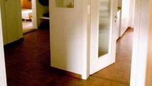 Un couloir carrelé qui mène à une pièce dotée d’une porte.