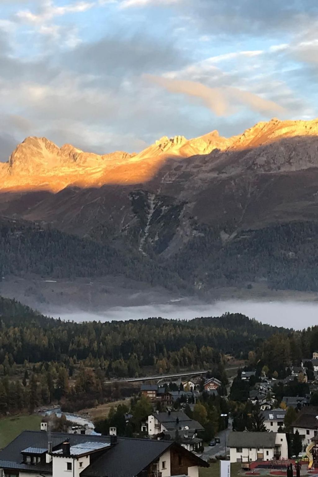 Ein Gebirge mit einem darunterliegenden Tal, Häusern und einer Brücke.