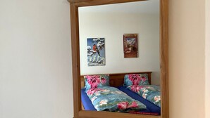 Ein Schlafzimmer mit einem spiegelnden Holzbett, blumigem Bettbezug und zwei an der Wand hängenden Bildern.