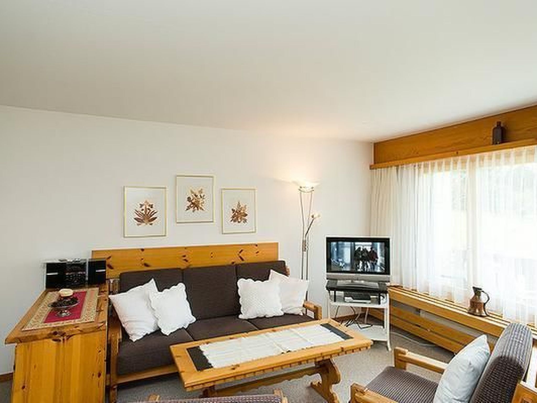 Een woonkamer met een bank, salontafel, televisie en kunst aan de muur.