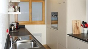 A compact kitchen with a sink, countertop, and a window. - Chesa Muragls by Interhome (Pontresina)