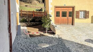 A building with a stone facade, wooden doors, and a small window. - Chesa Kober; Giarsun by Interhome (Pontresina)