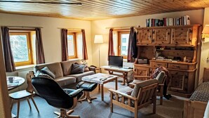 A cozy living room with a sofa, chairs, a desk, and a bookshelf. - Chesa Kober; Giarsun by Interhome (Pontresina)