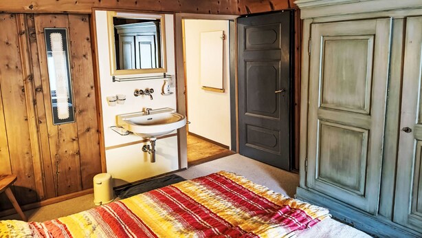 A wooden room with a bed, a sink, and a wardrobe. - Chesa Kober; Giarsun by Interhome (Pontresina)