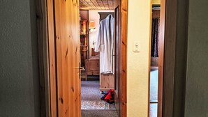 A wooden door leading to a room with a bed, a wardrobe, and a hanging garment. - Chesa Kober; Giarsun by Interhome (Pontresina)