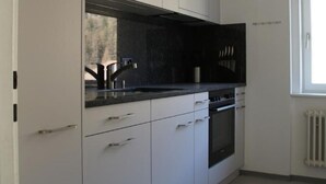 Uma cozinha moderna com armários brancos, bancada preta e eletrodomésticos de aço inoxidável.