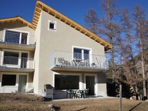 Edifici de dues plantes amb un balcó, un garatge i una petita zona d'estar a l'aire lliure.