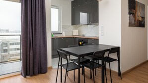A modern kitchen with dark cabinets, a black dining table, and black chairs. - Ursus Spacious Apartment (Warszawa)