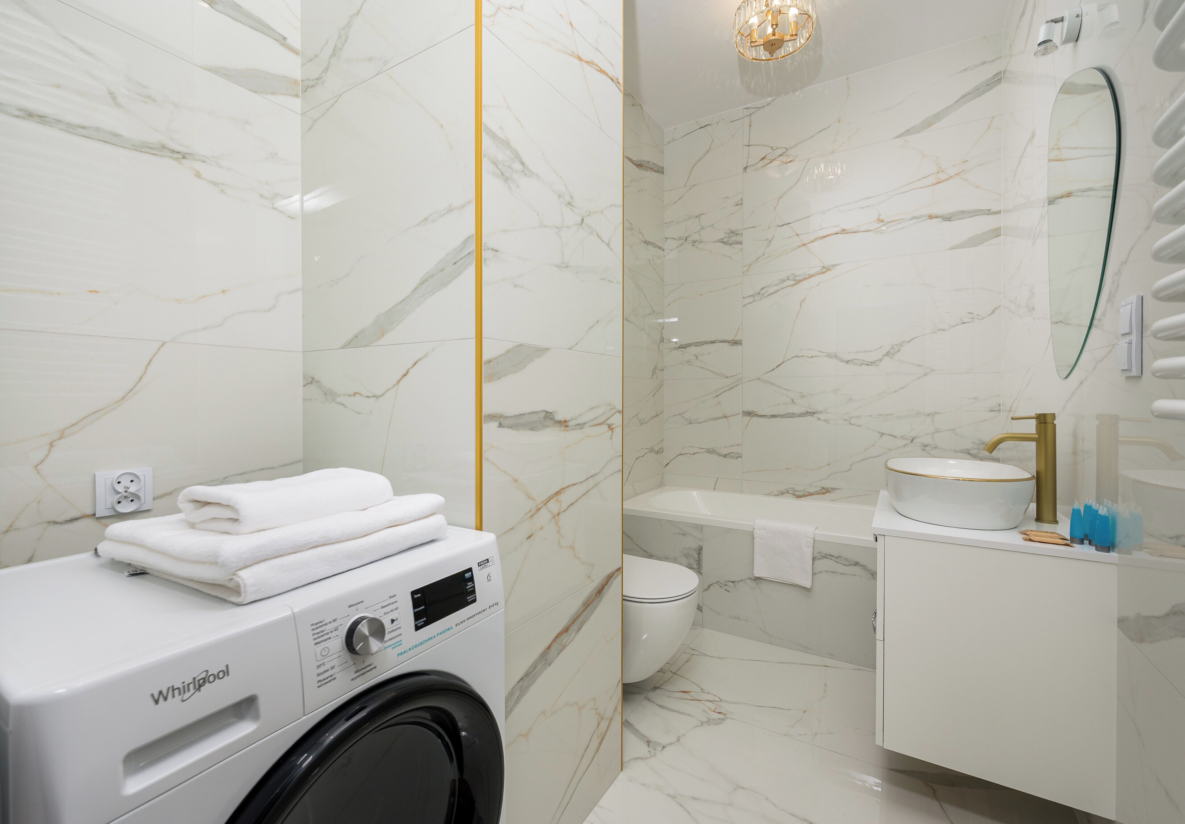 Un baño moderno con lavadora Whirlpool, inodoro, bañera y tocador con lavamanos.