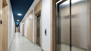 A long, narrow hallway with wooden paneling on the walls and a tiled floor. - Ursus Spacious Apartment (Warszawa)