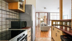A kitchen with a microwave, oven, and refrigerator. There is a wooden cabinet and a countertop. - Bemowo 2-Bedroom Apartment (Warszawa)