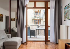 Un salon moderne avec un canapé, une table basse en bois et un balcon équipé d’une table et de chaises.