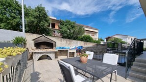 An outdoor patio with a grill, seating, and a view of the neighborhood. - Nina 2 pax by Interhome (Crikvenica)