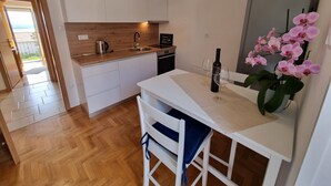 A modern kitchen with white cabinets, a wooden countertop, and a dining area with a white table and chairs. - Nina 2 pax by Interhome (Crikvenica)