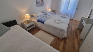 Ein modernes Schlafzimmer mit Bett, Nachttischen, einem Tischchen, einem Gemälde und einem Fenster mit Vorhängen.