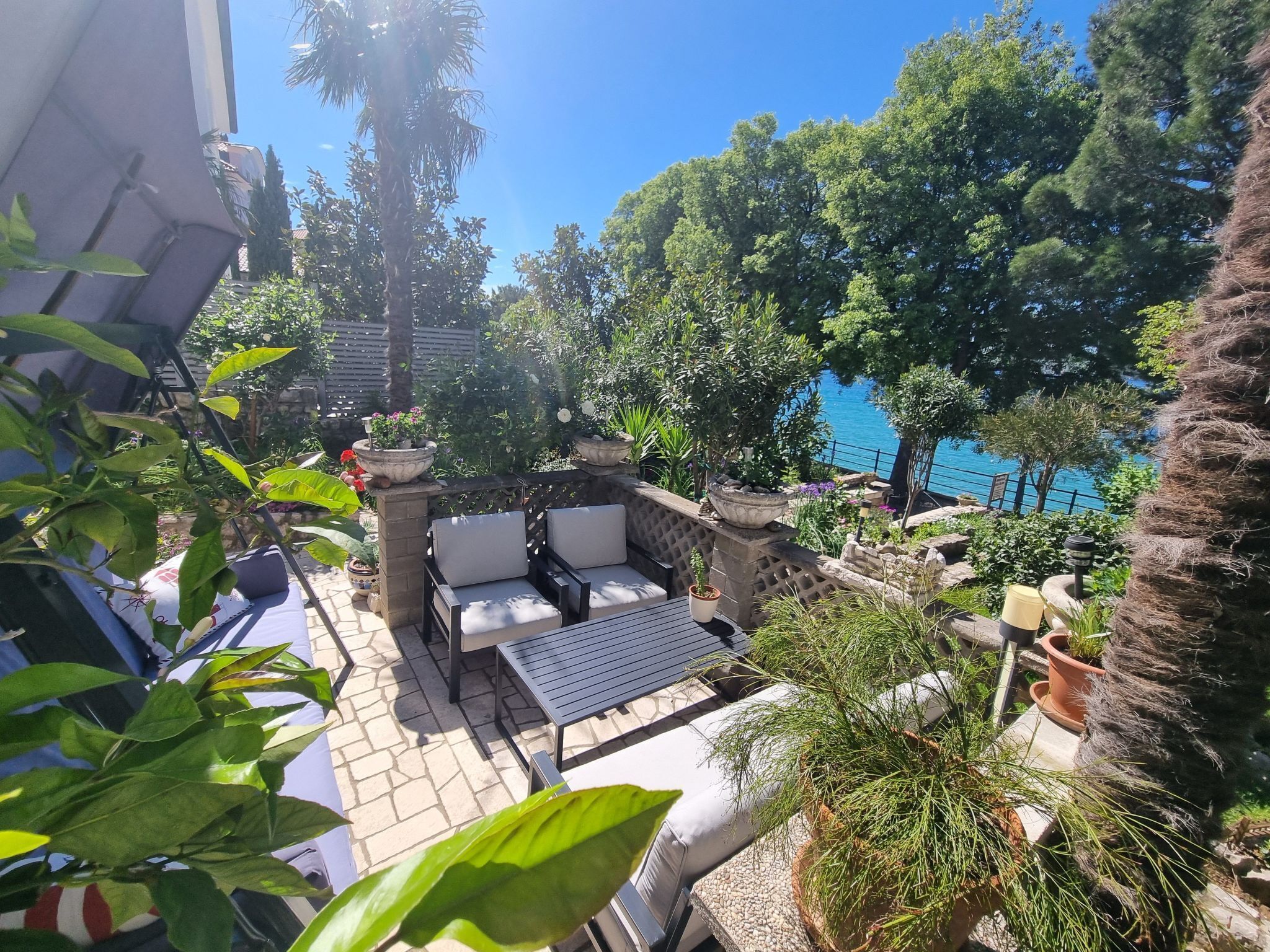 A patio with outdoor furniture, a stone wall, and potted plants.