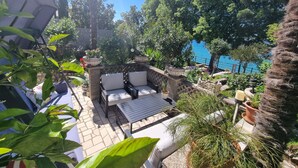 Eine Terrasse mit Gartenmöbeln, einer Steinmauer und Blumentöpfen.