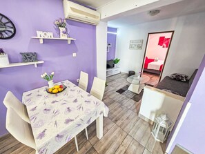 A dining area with a table set for two, a small shelf with decorative items, and a wall-mounted air conditioner. - Wohnung für 3 Personen mit Terrasse by Interhome (Crikvenica)