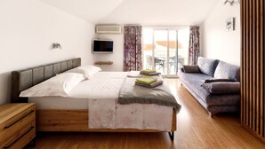 A modern bedroom with a large bed, a sofa, a TV, and a balcony with a view. - Studio-Apartment mit Balkon und Meerblick by Interhome (Crikvenica)