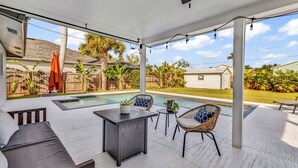 Un patio cubierto con piscina, mobiliario exterior y vistas al jardín trasero.