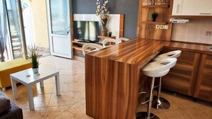 Una cucina moderna con isola in legno, sgabelli da bar bianchi e un'area pranzo con un tavolino e sedie.