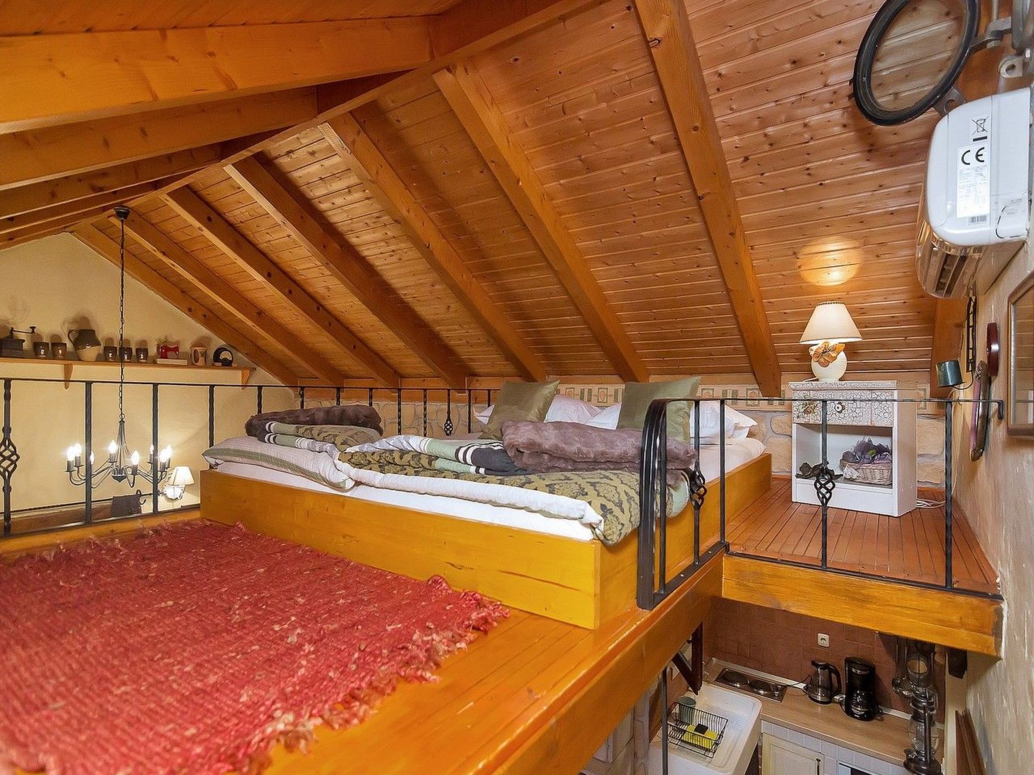 Ein Schlafzimmer im Loft-Stil mit Holzbalkendecke, einem Etagenbett, einem kleinen Schreibtisch mit Lampe und einer Heizung.