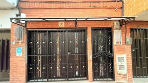 Une entrée fermée par un portail, avec un panneau indiquant les heures d’ouverture du parking.