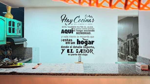 Une cuisine avec un mur décoratif orné d’une citation en espagnol.