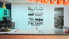 A kitchen with a decorative wall featuring a quote in Spanish. - Laureles Co-Living Casa 5 habitaciones (Medellín)