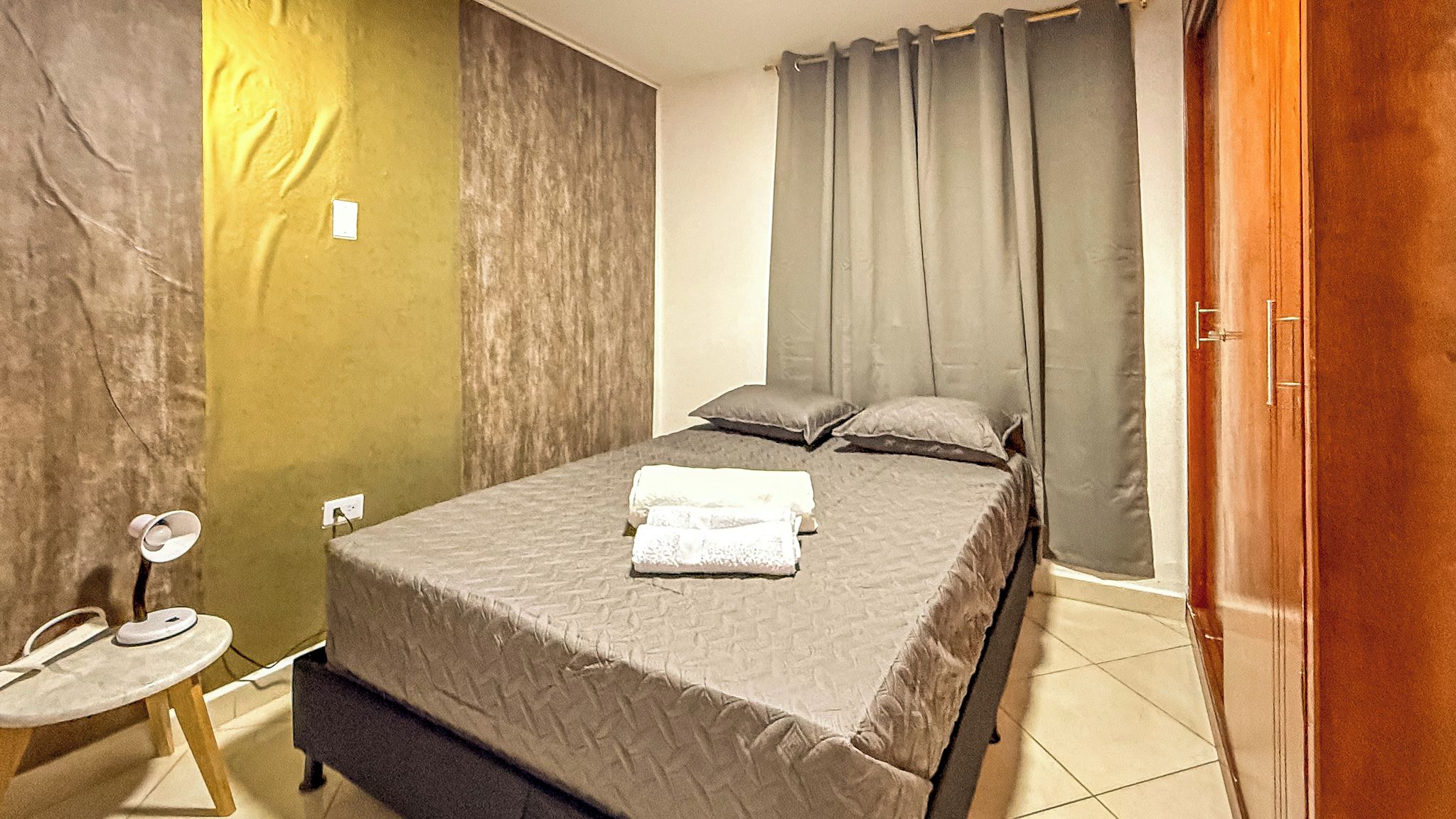 Ein Schlafzimmer mit Bett, Kissen, Nachttisch und Tür.