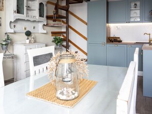 A kitchen with white and blue cabinets, a wooden staircase, and a table with a glass jar and seashells. - Schönes Haus in Makarska mit privatem Parkplatz by Interhome (Makarska)
