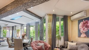 A spacious living room with a modern sofa, a pink armchair, and a dining area with a table and chairs. - Schönes Appartement am Strand mit Terrasse by Interhome (Makarska)