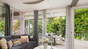 A modern living room with a grey sofa, a white coffee table, and a view of a garden through large windows. - Schönes Appartement am Strand mit Terrasse by Interhome (Makarska)
