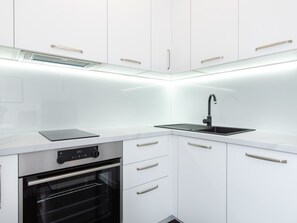 Een koelkast, een oven, kookgerei, borden en bestek