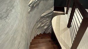 Una scala con ringhiera in legno e parete strutturata.