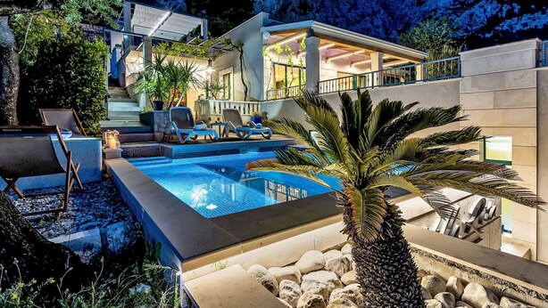 A modern villa with a swimming pool, outdoor seating, and a mountain backdrop. - "Villa Rita" mit Blick auf das Wasser by Interhome (Makarska)