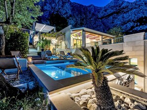 Une villa moderne dotée d’une piscine, d’un espace salon extérieur et offrant une vue sur les montagnes.