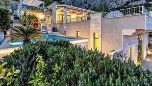 A modern villa with a swimming pool, outdoor seating, and a mountain backdrop. - "Villa Rita" mit Blick auf das Wasser by Interhome (Makarska)