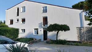 Un edificio de dos pisos con fachada blanca, varias ventanas y un pequeño balcón.