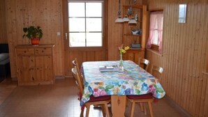Una stanza con rivestimento in legno, un tavolo da pranzo, sedie, un piccolo armadietto e una finestra.