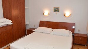Une chambre à coucher avec un lit en bois, deux tables de chevet, une armoire et des lampes fixées au mur.
