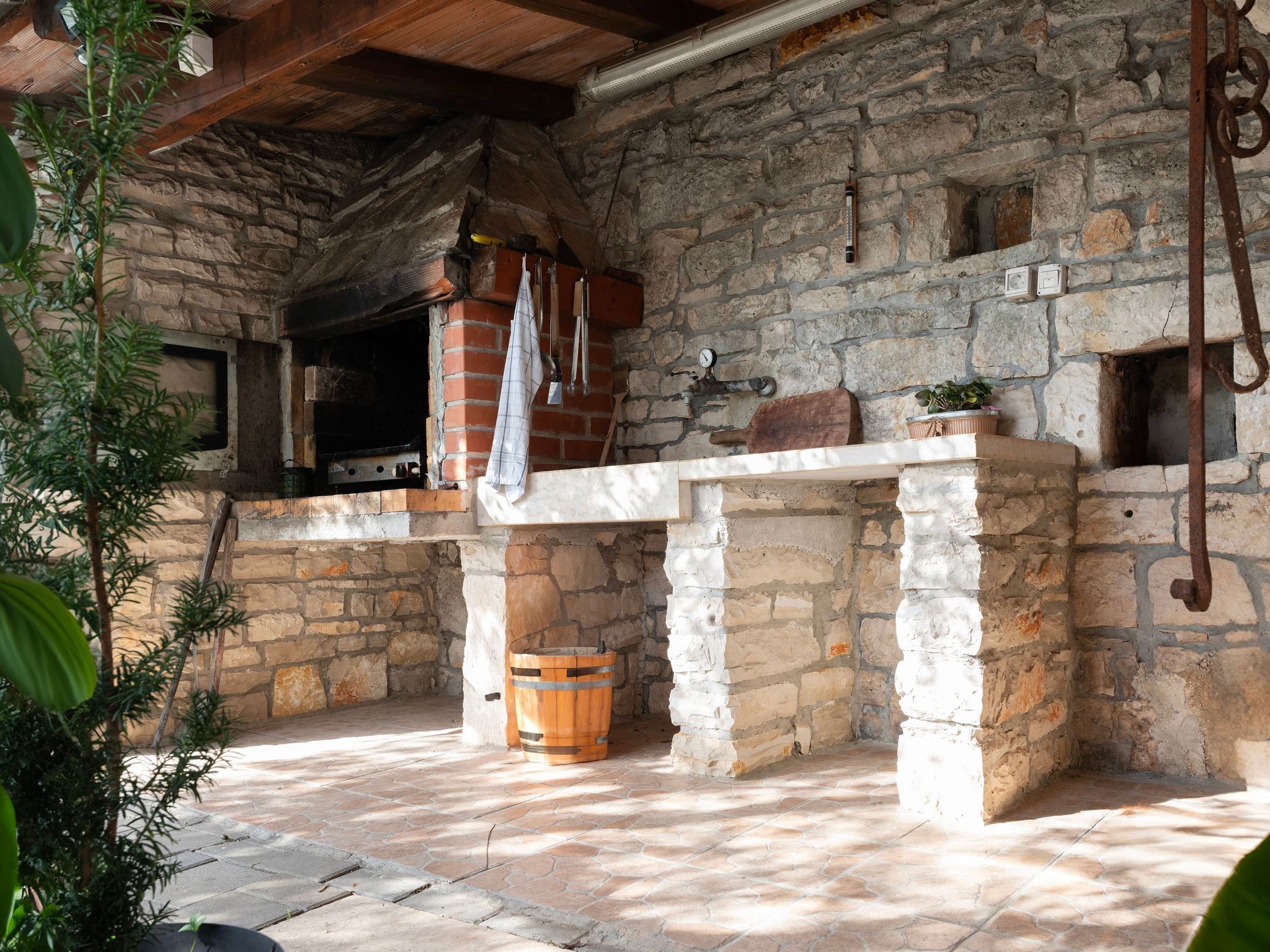 A rustic stone interior with a brick oven, a wooden barrel, and a stone wall.